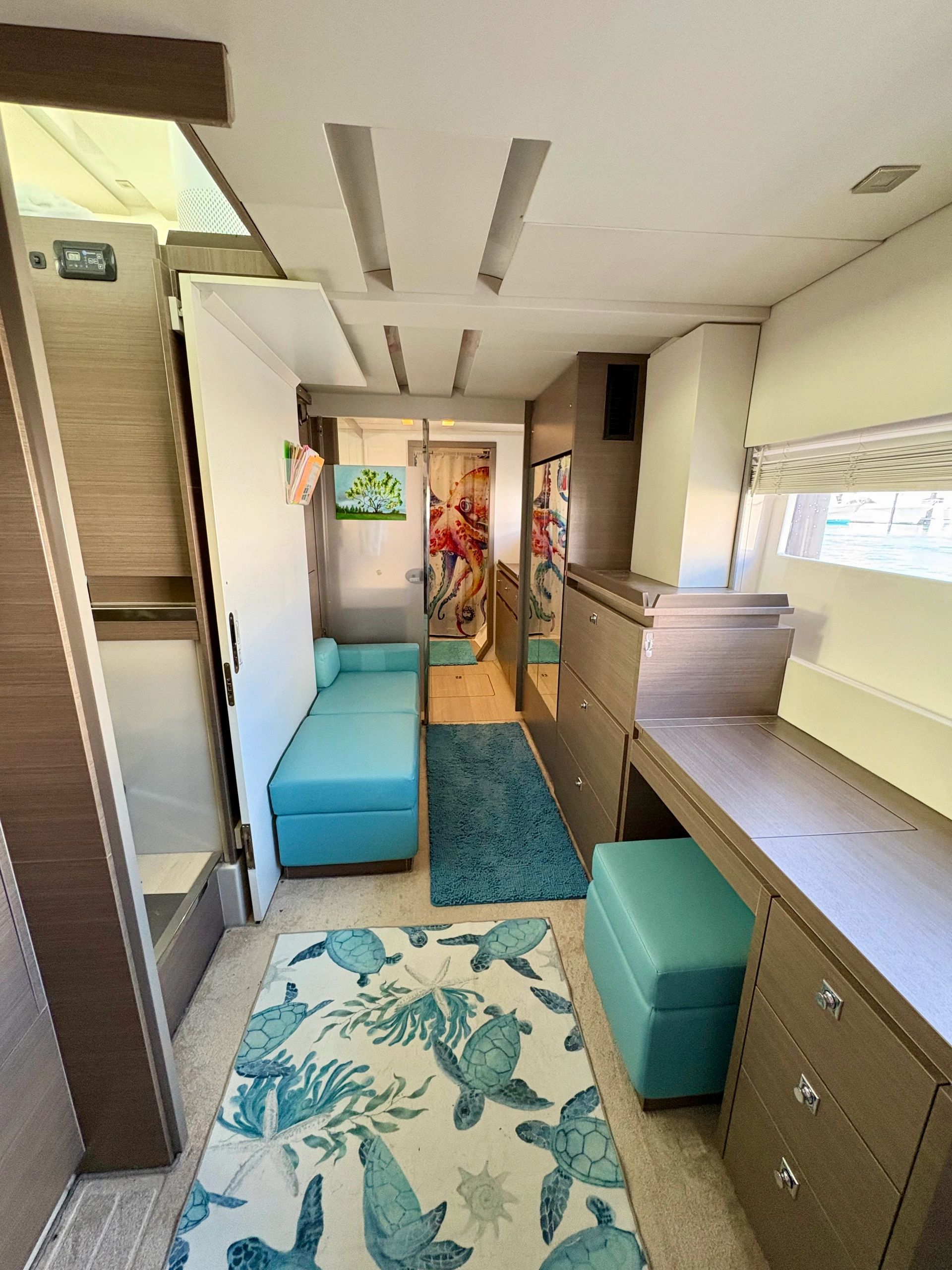 Compact and cozy marine interior with turquoise cushions and sea turtle rugs.