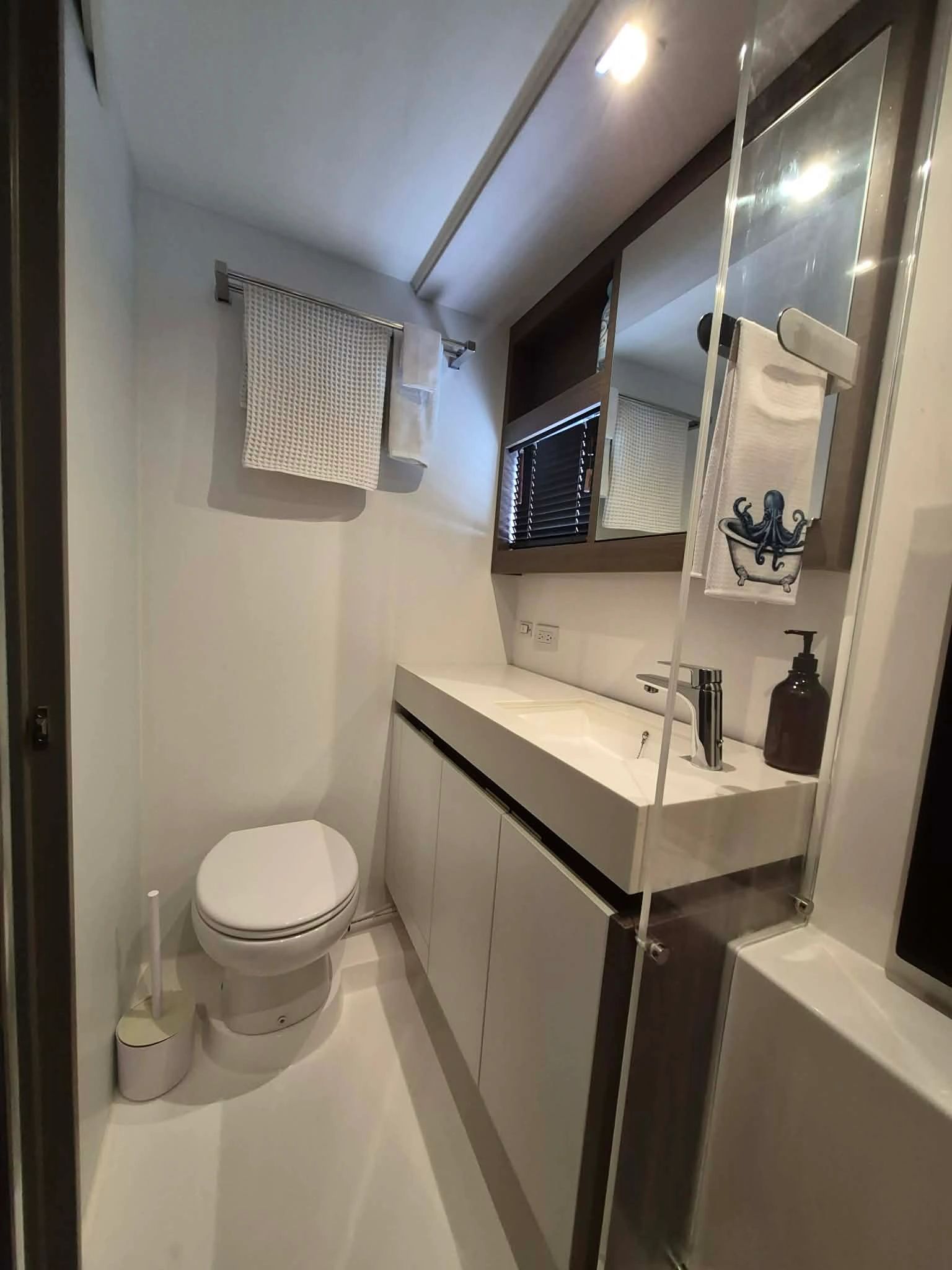 Modern bathroom with white fixtures and octopus-themed towel.