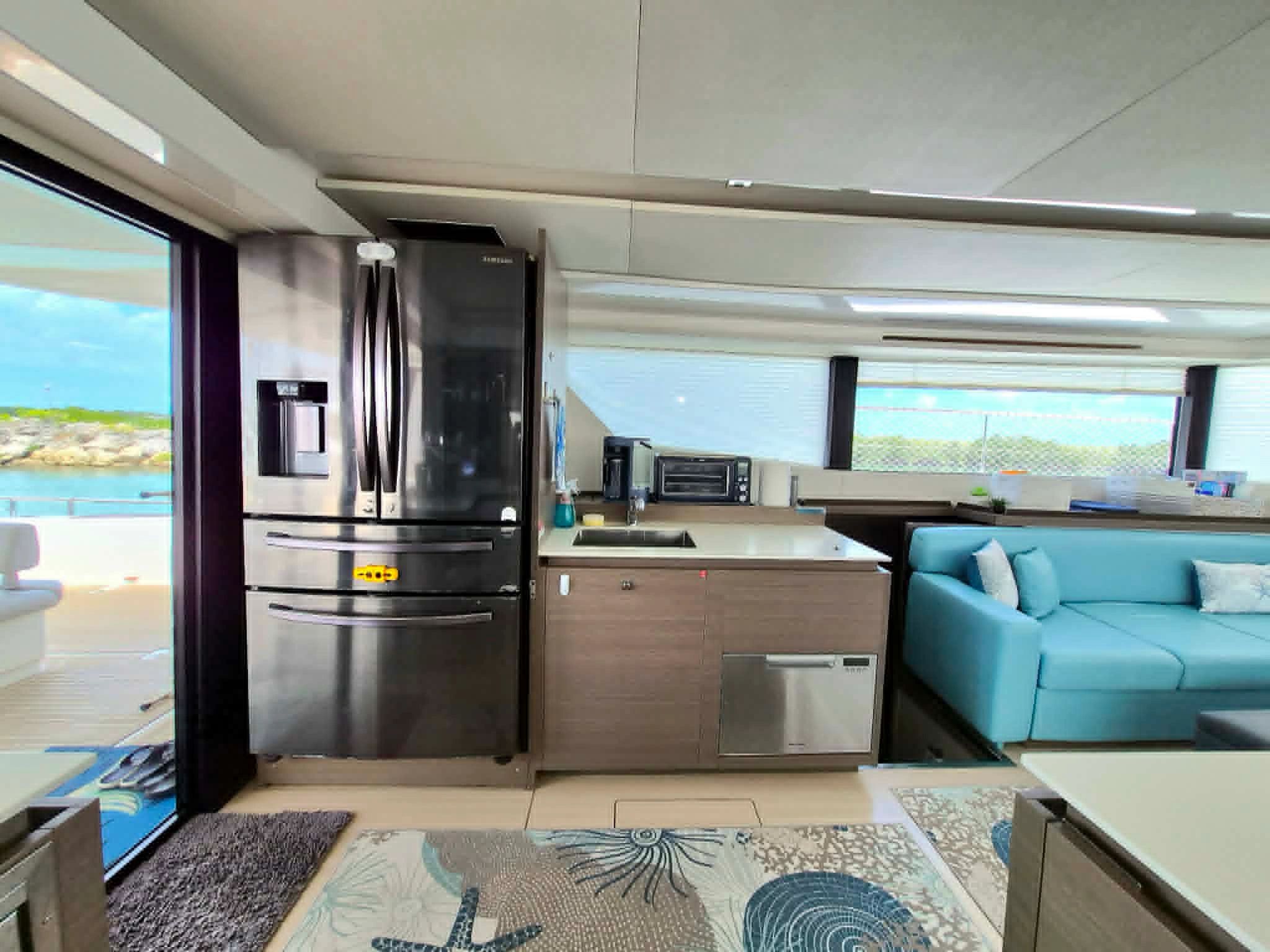 Modern kitchen area with stainless steel fridge and sea view.