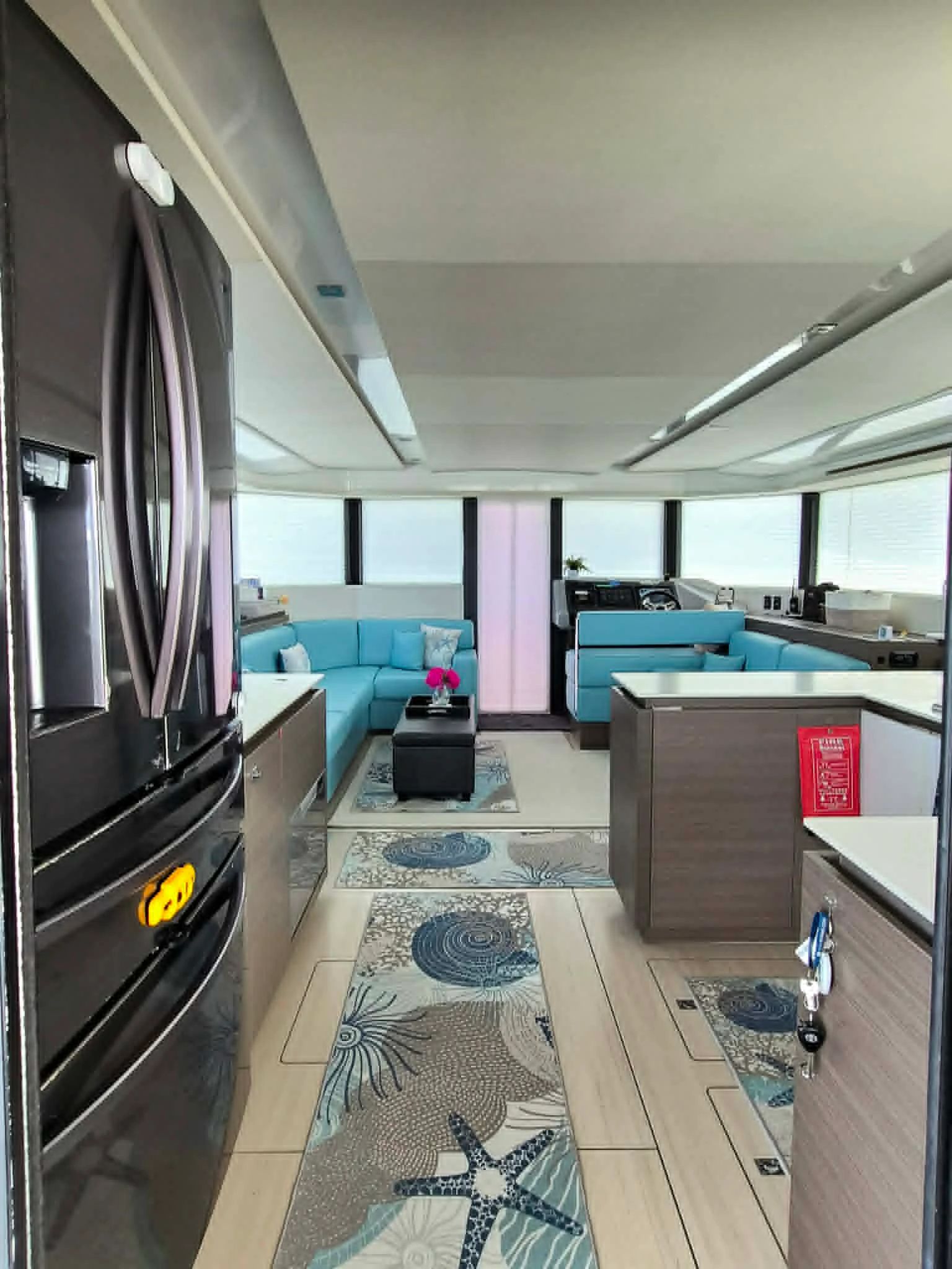 Modern yacht interior with turquoise seating and ocean-themed rugs.