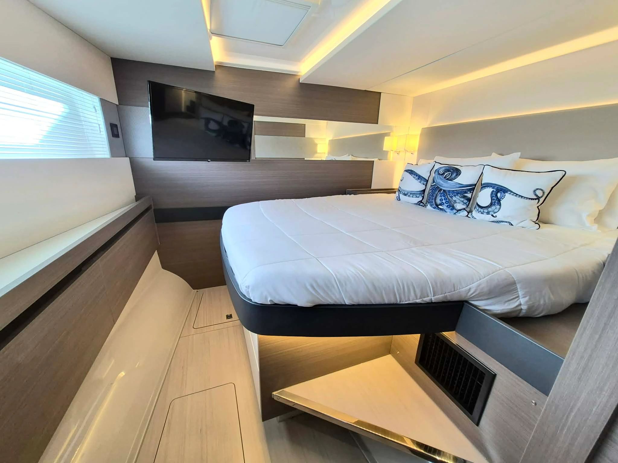 Modern bedroom with a TV, white bedding, and octopus-themed pillows.