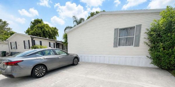 Silver car parked beside a white mobile home.