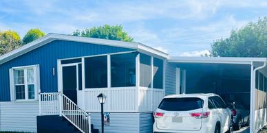 Blue and white house with a screened porch and parked cars.