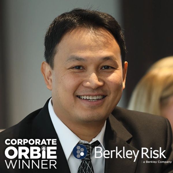 Smiling man in suit with Corporate ORBIE Winner and Berkley Risk logos.