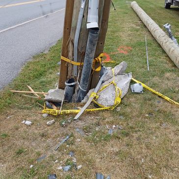 Damaged utility pole surrounded by caution tape.