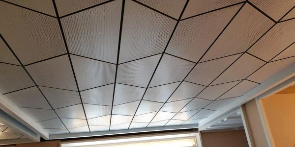 Ceiling with geometric-patterned tiles and recessed lighting.