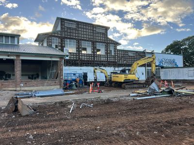 Construction site with excavators and building framework under a cloudy sky.