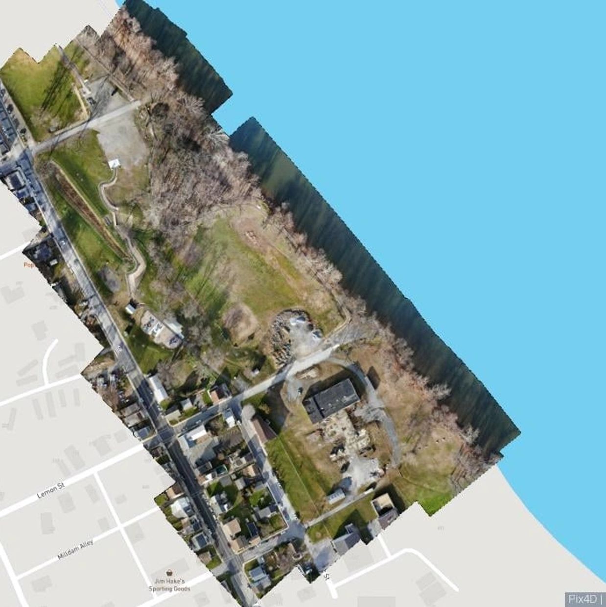Aerial view of a riverside neighborhood with houses and green spaces.
