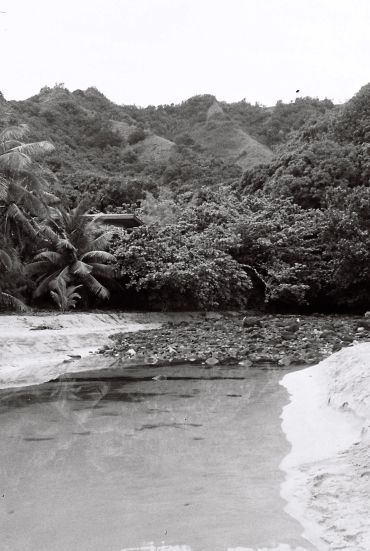 A tranquil river flowing through lush tropical forest and hills.