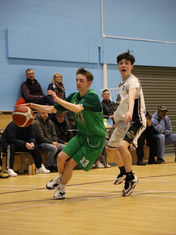 Two young basketball players competing intensely during a game indoors.