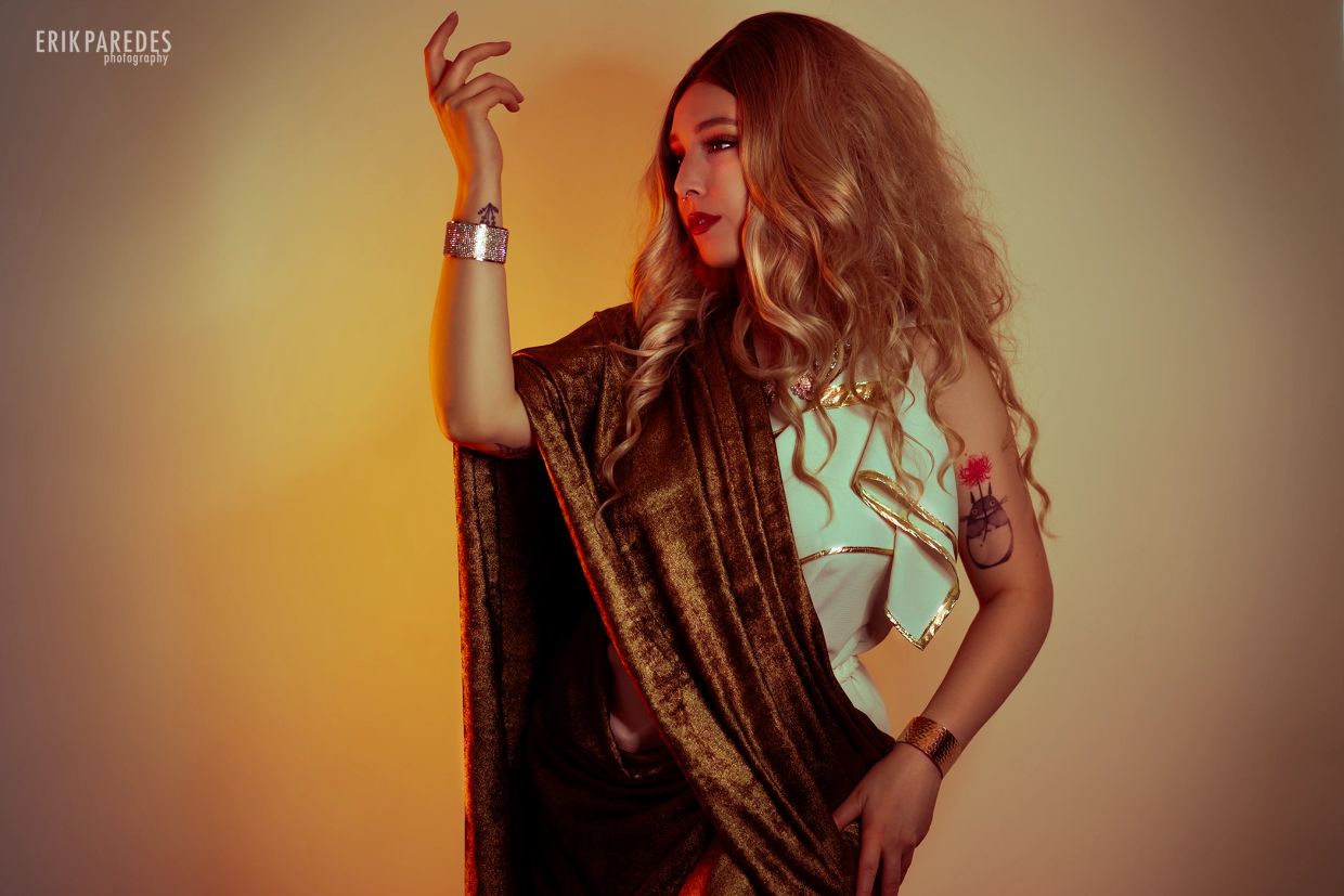 Woman in golden and white outfit striking a graceful pose.