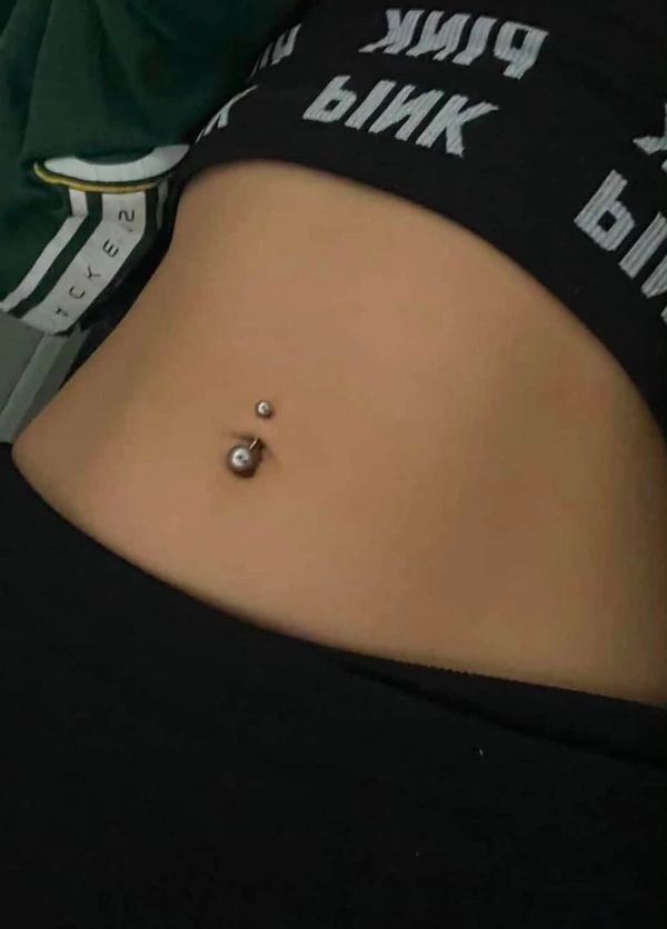 Close-up of a belly button piercing with silver jewelry.
