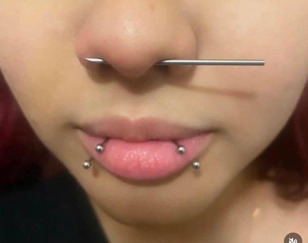 Close-up of facial piercings including a nose and lip piercings.