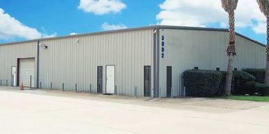 A large industrial warehouse building with a metal exterior under a blue sky.