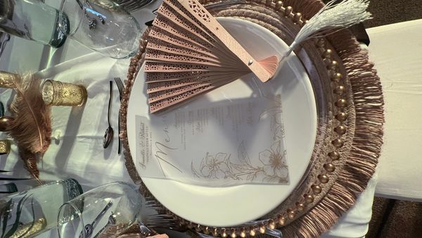 Elegant table setting with a decorative fan and menu on a white plate.