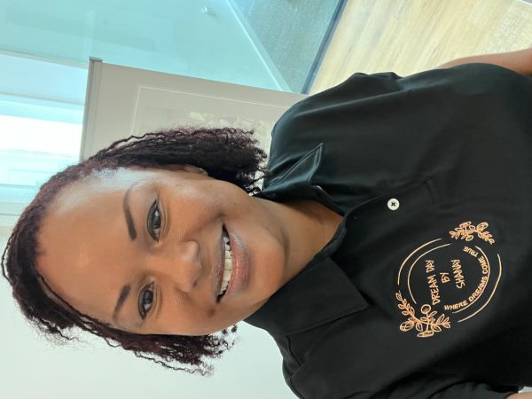 Smiling woman wearing a black polo shirt with embroidered logo in a bright room.