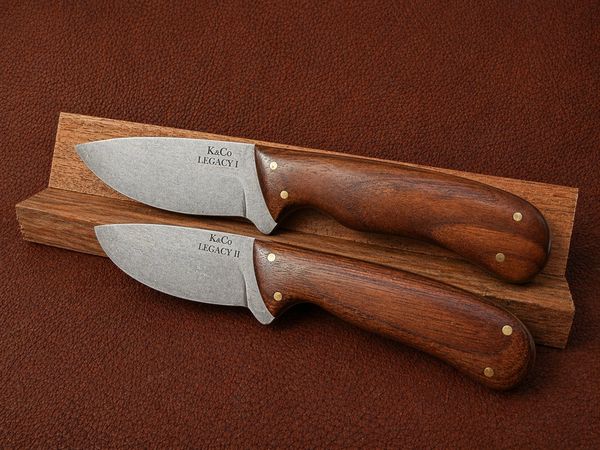 Two handcrafted knives with wooden handles on a wooden stand.