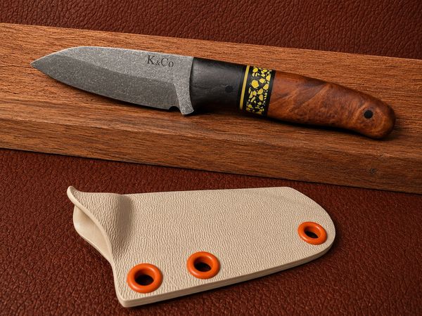 Crafted hunting knife with wooden handle and protective sheath on leather surface.