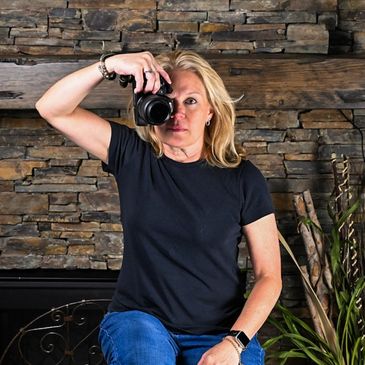 Woman in black shirt taking a photo with a camera indoors.