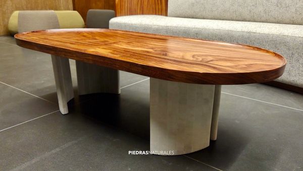 Modern oval wooden coffee table with sturdy stone legs on a dark tiled floor.