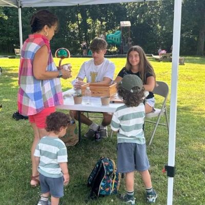 Kids and adults gathered under a tent at an outdoor event.
