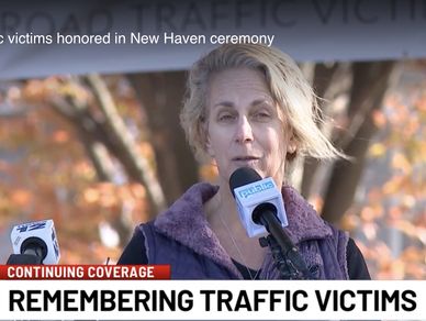 Woman speaking at a memorial ceremony for traffic victims in New Haven.