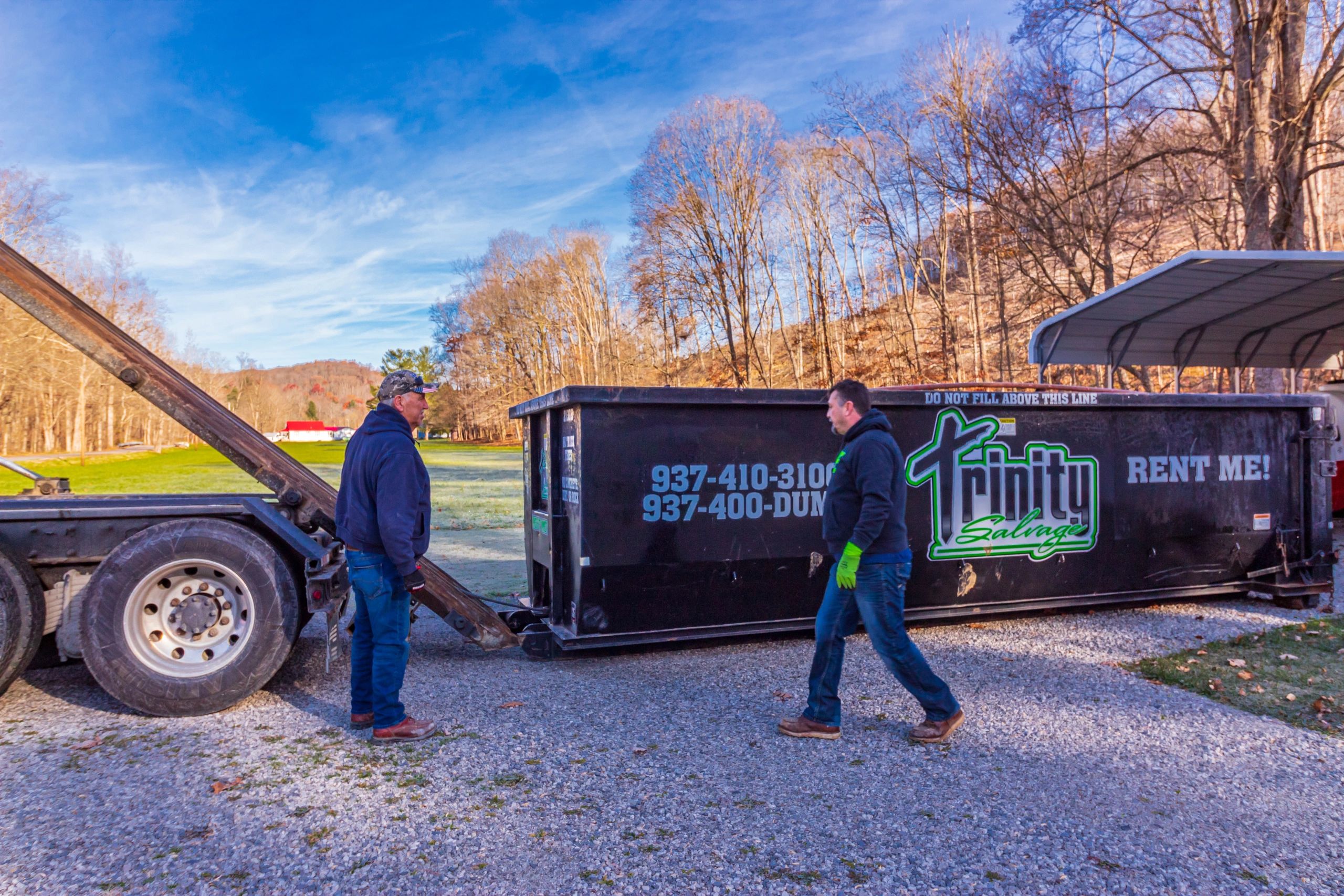 Head driver Jeff Daniels and owner Kevin Schoonover prepare a dumpster to be loaded