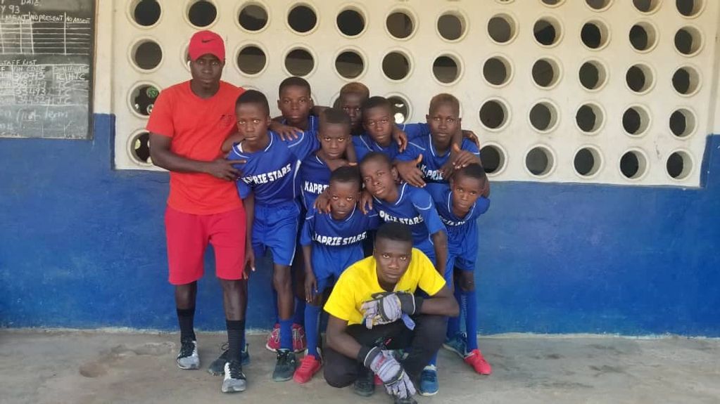 A youth soccer team posing indoors with their coach.