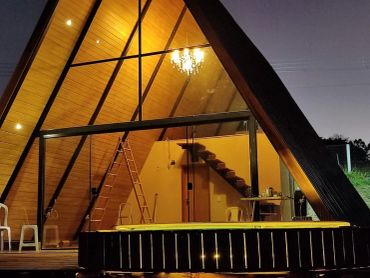Casa A-frame iluminada à noite com piscina.