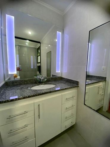 Banheiro moderno com pia e espelho iluminado.