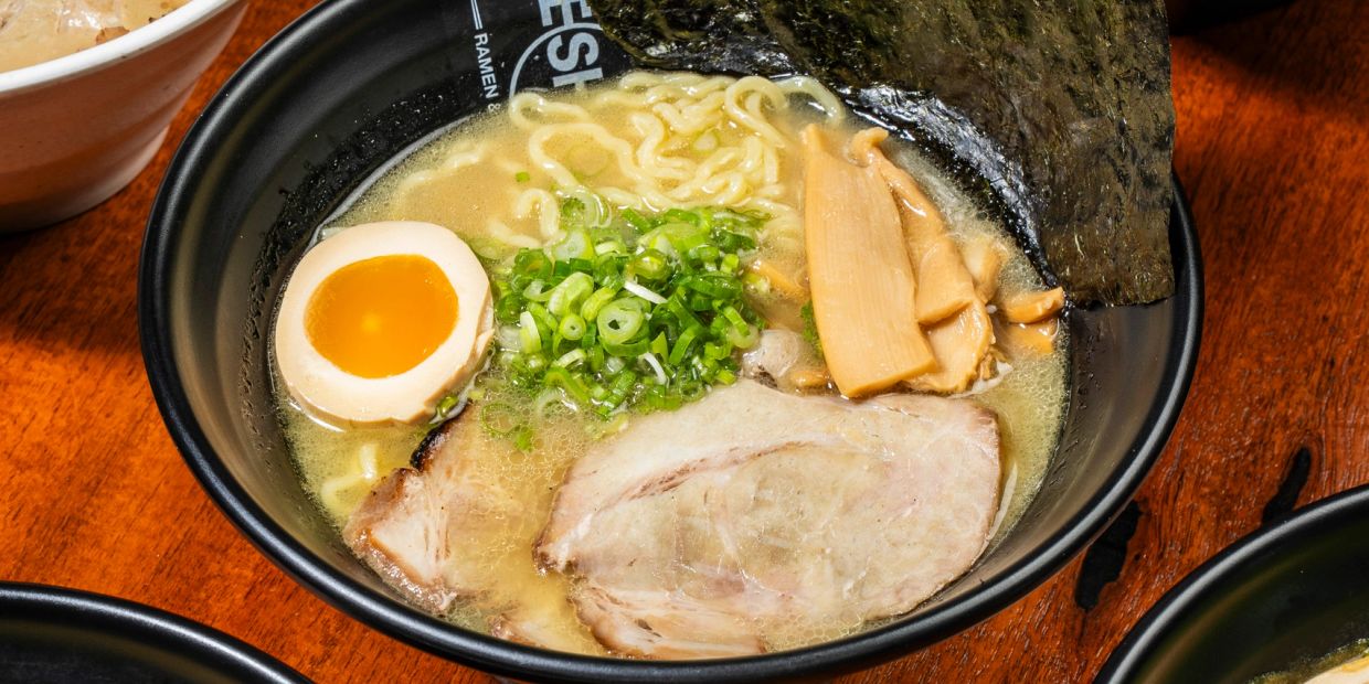 A bowl of ramen with egg, pork, green onions, and seaweed.