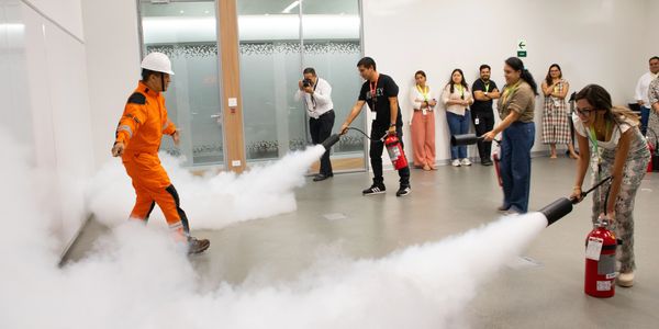 People practicing fire extinguisher use in a safety drill indoors.
