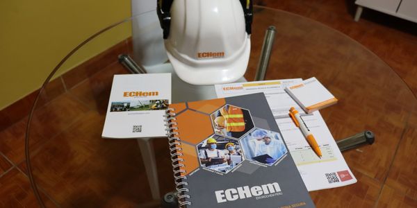 Promotional materials and a safety helmet from ECHEM on a glass table.