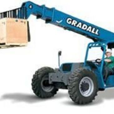 Blue Gradall forklift lifting a large crate.