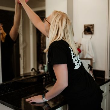 Person cleaning a mirror in a bathroom.