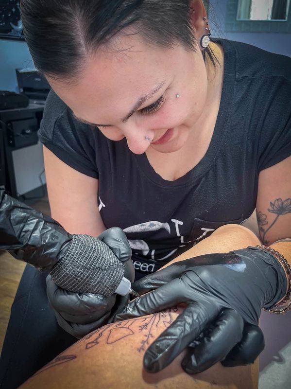 Tattoo artist working on a client's leg tattoo.