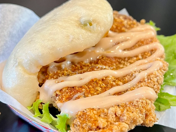 Crispy fried chicken with sauce in a steamed bun and lettuce.