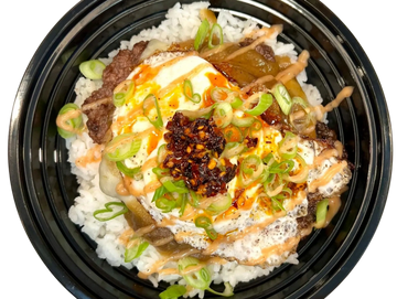 Rice bowl with fried egg, beef, scallions, and spicy sauce in a black container.