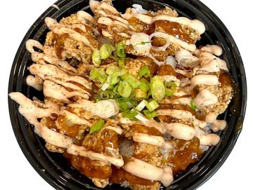 Crispy chicken topped with creamy sauce and green onions in a black bowl.