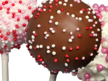 Three colorful cake pops with sprinkles on white sticks.