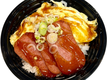 Rice bowl with fried egg, sliced spam, sauce, and green onions in a black container.