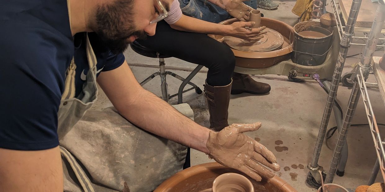 Three people shaping pottery on wheels in a cozy workshop.