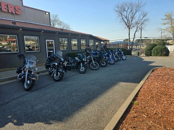 A row of motorcycles parked outside a building on a sunny day.