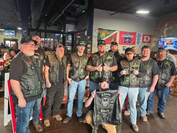 A group of bikers wearing leather vests with patches inside a bar.