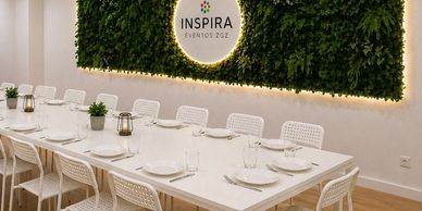 Elegant dining area with white chairs and green wall at Inspira Eventos.
