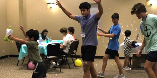 Kids and teens playing with bubbles indoors, having fun together.
