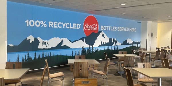 Mural promoting 100% recycled Coca-Cola bottles in a dining area.
