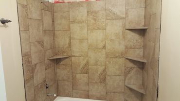 Tiled shower walls with corner shelves.