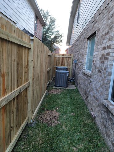 Narrow backyard space between two houses with an air conditioning unit.