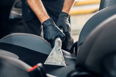 Hot water extractor cleaning a car interior for interior deep clean